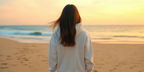 Woman enjoying a sunset on the beach with waves in the background