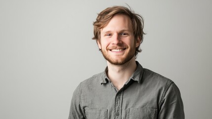 Obraz premium A smiling young man with tousled hair poses against a neutral background.