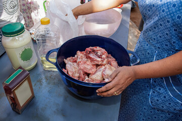 village african woman motswana dress, preparing raw chicken with spices on a table outdoors