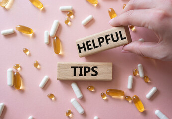 Helpful tips symbol. Concept word Helpful tips on wooden blocks. Doctor Hand. Beautiful pink...