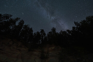 Sandstone Suur Taevaskoja, forest and starry sky with the Milky Way. Nature of Estonia.