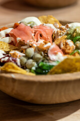 Close up of nachos fries with shredded chicken meat, vegetables, Healthy vegan salad bowl in wooden bowl, poke bowl