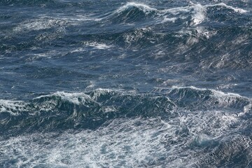 Dynamic ocean waves create mesmerizing pattern of blue and white foam, showcasing power and beauty of nature