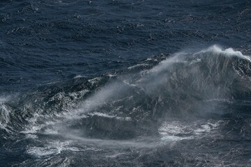 Dark ocean waves crashing with powerful force, creating mist and foam. turbulent sea showcases nature raw energy and beauty