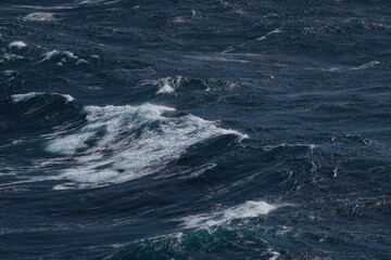 Waves crashing on dark ocean surface, creating dynamic and powerful scene. turbulent water showcases various shades of blue and white foam