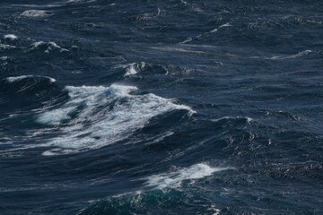 image captures dynamic movement of ocean waves, showcasing deep blue hues and frothy white crests. scene evokes sense of tranquility and power of nature