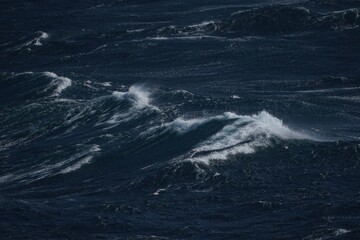 Dark ocean waves crashing against each other, creating dramatic seascape. turbulent water reflects sense of power and nature beauty