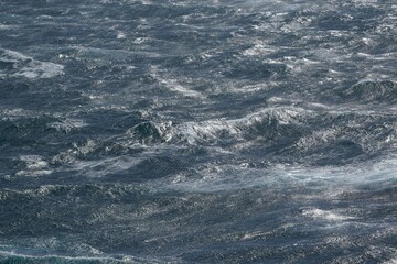 image captures dynamic movement of ocean waves, showcasing interplay of light and water. turbulent sea reflects range of blues and grays, creating sense of depth and energy