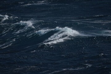 Dark ocean waves crashing with white foam create dramatic seascape. turbulent water showcases power and beauty of nature, evoking sense of awe and tranquility