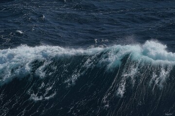 Majestic ocean waves crashing against each other, creating dynamic and powerful scene. deep blue water contrasts beautifully with white foam, evoking sense of tranquility and strength