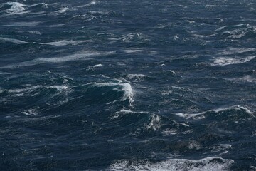 Dark ocean waves with white foam creating dynamic seascape. turbulent water reflects sense of power and movement, showcasing nature raw beauty