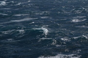 Dark ocean waves with white foam creating dynamic seascape. turbulent water reflects moody atmosphere, showcasing nature power and beauty