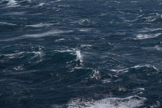 image captures turbulent ocean surface with dark, choppy waves creating dramatic and powerful scene. movement of water evokes sense of energy and intensity