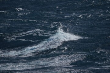 image captures turbulent ocean waves, showcasing dynamic movement of water in deep blue sea. scene evokes sense of power and tranquility