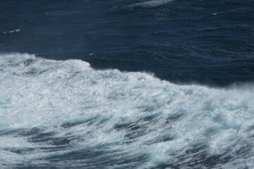 Waves crashing on turbulent ocean surface create dynamic scene of nature power and beauty. deep blue water contrasts with white foam, evoking sense of tranquility and awe