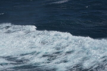 Waves crashing on deep blue ocean create dynamic and powerful scene. contrast between white foam and dark water evokes sense of nature raw energy and beauty