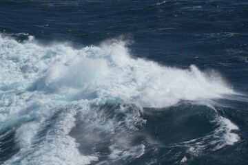 Powerful ocean waves crashing against each other, creating dramatic scene of white foam and deep blue water, showcasing beauty and force of nature