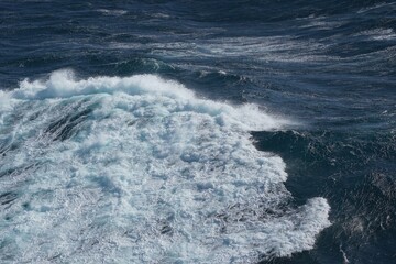Waves crashing on ocean surface, creating dynamic and vibrant scene. deep blue water contrasts with white foam, evoking sense of power and tranquility