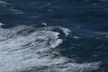 Rough ocean waves create dynamic scene with deep blue water and white foam. powerful movement of sea evokes sense of nature strength and beauty