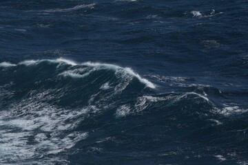Majestic ocean waves crashing against each other, creating dynamic seascape. deep blue water contrasts with white foam, evoking sense of power and tranquility
