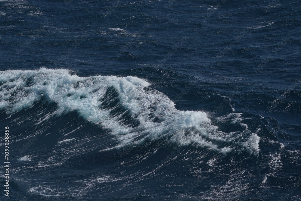 Poster waves crashing on deep blue ocean create dynamic and powerful scene. contrast of white foam against 