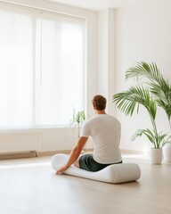 Male kneeling with an orange foam roller in a bright room, ideal for fitness, stretching, and physical therapy themes