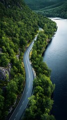 Fototapeta premium Serene landscape of a winding road beside a calm river surrounded by lush greenery.