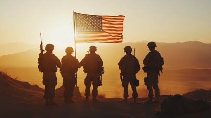 Four soldiers stand in silhouette with an American flag in the desert at sunset.