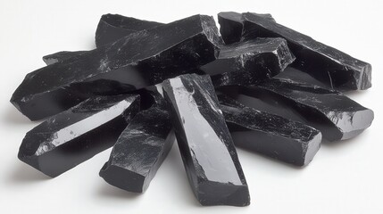 A collection of shiny black obsidian stones arranged on a white surface.