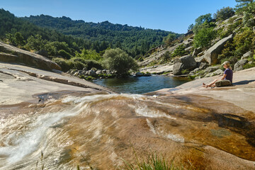 Woman sitting on a rock in front of a pond