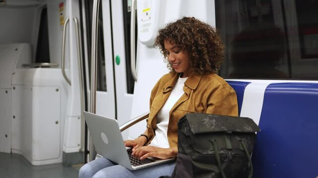 Young woman working on laptop in subway in slow motion. Young woman riding the subway while working on her laptop in slow motion captures the essence of modern commuting