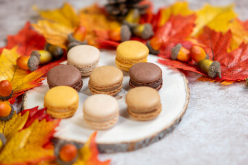 French pastry macarons, Autumn home cozy composition, macaroons autumn leaves and bokeh on a wooden background.