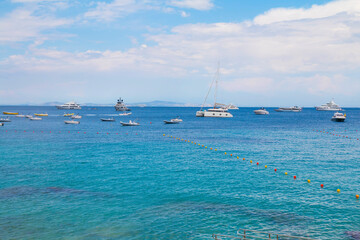The photo captures a view of Capri from the water, showcasing the island's iconic cliffs, colorful buildings, and lush greenery set against the clear blue sea and sky.