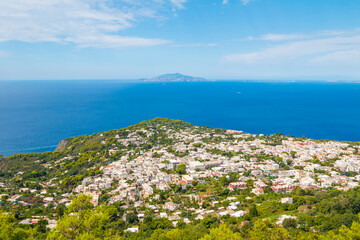 Obraz premium The photo offers a scenic view from the cable car to Anacapri, Italy, showcasing sweeping landscapes, vibrant greenery, and the azure sea, capturing the beauty of this stunning island route.