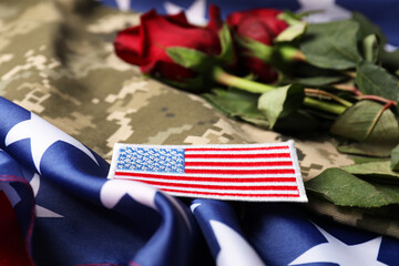 Veterans day. USA army patch, rose flowers and military uniform on American flag, closeup