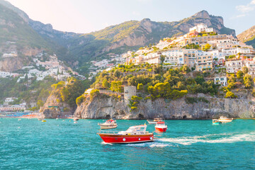 Obraz premium The photo captures a sunny view of Amalfi, showcasing the town's colorful buildings, steep cliffs, and vibrant coastline under a clear blue sky on a bright day.