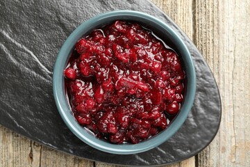 Tasty cranberry sauce in bowl on wooden table, top view