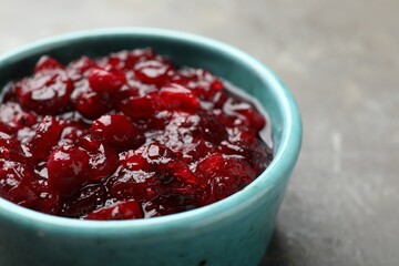 Tasty cranberry sauce in bowl on grey table, closeup