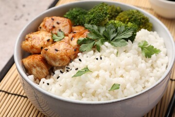 Tasty rice with broccoli, chicken and parsley on table, closeup