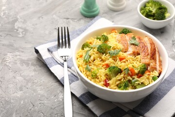 Tasty rice with vegetables and chicken served on grey table, closeup