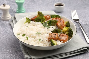 Tasty rice with broccoli and chicken served on grey table, closeup