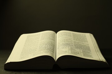 Open Holy Bible in English language on black table, closeup