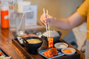 Woman hand holding chopsticks for eating Kimchi salad in restaurant. Japan food traditional Kimchi