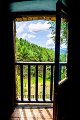 View from the window of a rustic house towards a beautiful landscape of mountains, trees and nature	