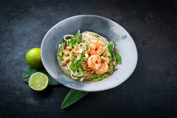 Authentical Asia style ramen noodle soup with prawns and cashew nuts served as close-up in a design bowl