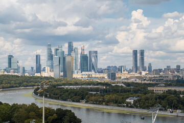 Obraz premium Luzhniki Park offers a stunning view of the Moscow City skyline, framed by lush greenery and dynamic clouds above
