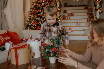 Cute kid decorates Christmas tree with toys with his mother