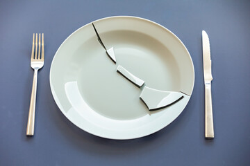 Empty plate top view with metal cutlery next to it. Broken plate