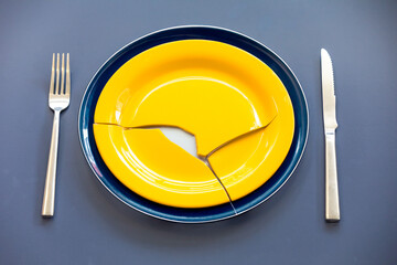 Empty plate top view with metal cutlery next to it. Broken plate