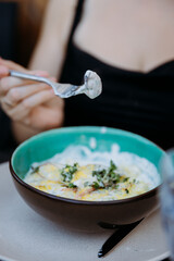Close up of creamy bite on a fork over a turquoise bowl of fresh gourmet salad and microgreens